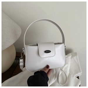 Détail du sac à main en cuir blanc brillant montrant la plaque du logo JWHN