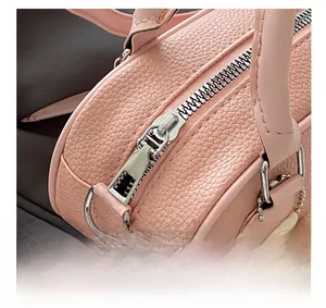 Close-up of silver metal zipper and pebble grain leather on pink minimalist handbag