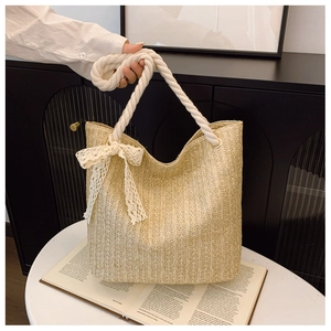 Detail of beige straw tote bag featuring thick cotton rope handles and white lace bows