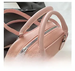 Detail of pink pebbled leather handbag featuring silver zipper and sturdy round handles