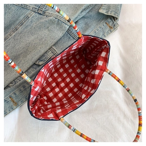 Top view of woven tote bag showing red checkered lining and multicolor braided handles