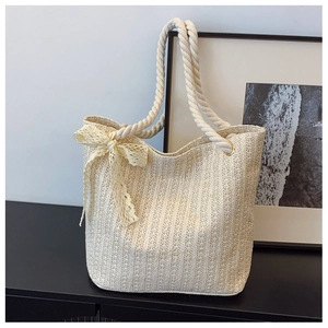 Detail view of woven straw tote bag with cream lace bow and thick cotton rope handle