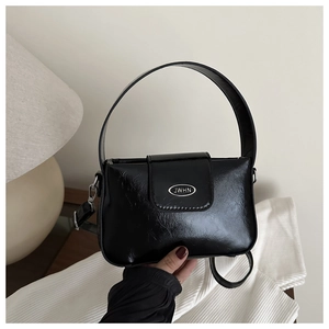 Détail du sac polochon noir en cuir ciré brillant avec plaque logo JWHN argentée