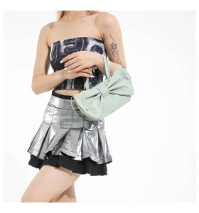 Detailed view of mint green bow-shaped handbag styled with silver metallic skirt