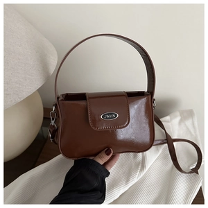 Détail du sac en cuir verni marron café avec boucle métallique ovale et poignée rigide
