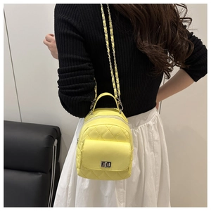 Nahaufnahme des gelben Mini-Rucksacks mit Rautensteppung und silberner Kette am Model