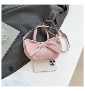 Close-up of pink bow handbag in washed fabric with phone for size reference