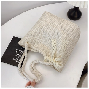 Close-up of woven straw tote bag with lace bow detail and rope handles on marble