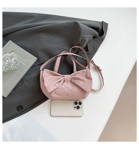 Pink bow handbag on grey suit fabric showing compact size next to a smartphone