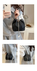 Detailed view of black crocodile pattern bucket bag with pearl tassels and silver chain straps
