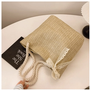 Detail of woven straw tote bag featuring white lace bow and thick rope handles