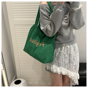 Detail of green canvas tote with orange Fayissa lettering, showing large capacity size