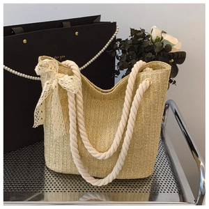Detailed shot of straw woven bag with white lace bow and sturdy cotton rope handle
