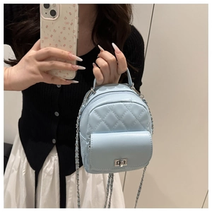Detail of mini quilted leather backpack featuring silver chain strap and metal lock closure