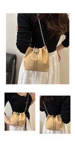 Detail of beige crocodile embossed bucket bag with butterfly clasp and pearl charms