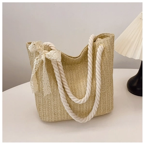 Detail of woven straw tote bag with cotton rope handles and beige lace bow decoration