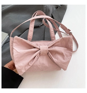 Detail of pink bow handbag showing wrinkled texture fabric and adjustable shoulder strap