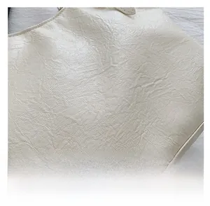 Macro detail of creamy white soft faux leather showing fine lychee grain texture