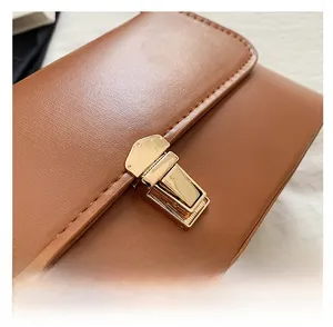 Gros plan sur un sac porté épaule en cuir marron avec boucle en métal doré