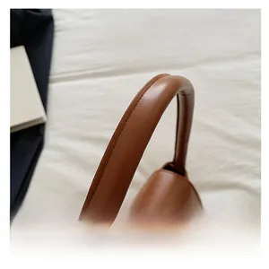 Détail des coutures renforcées sur la poignée en cuir marron du sac baguette