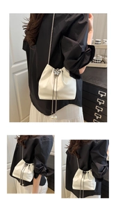 Detail of white drawstring bucket bag with metal butterfly clasp and pearl charms
