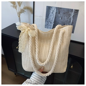 Detailed shot of beige woven straw tote bag featuring elegant lace bow and soft rope handles