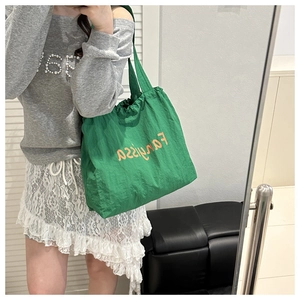 Detail of green canvas tote bag with orange print and adjustable drawstring closure