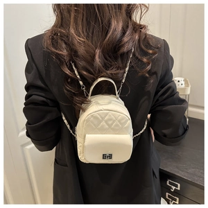 White quilted leather mini backpack with chain strap worn on a black blazer