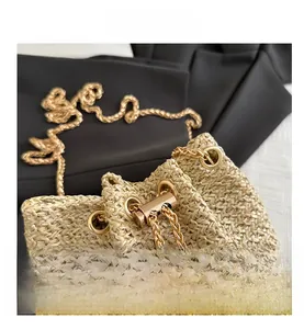 Close-up of beige woven straw bucket bag with gold chain strap and metal drawstring clasp