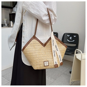 Detail of large woven straw tote bag featuring brown leather straps and V-shaped top opening