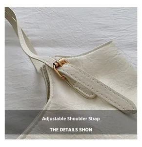 Detail view of adjustable shoulder strap with gold buckle on creamy white tote bag