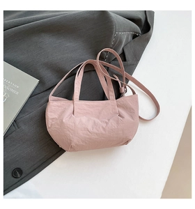 Detail of adjustable strap and light pink crinkled texture on a bow-design handbag
