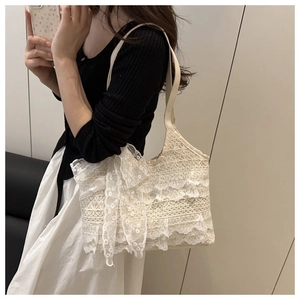 Close-up of cream lace tote bag with oversized bow detail worn by a model