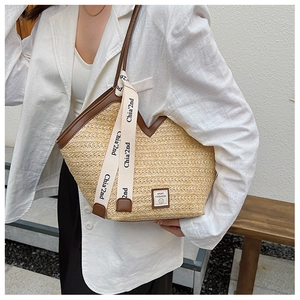 Detail of woven straw tote bag with brown leather trim and stylish letter print ribbon