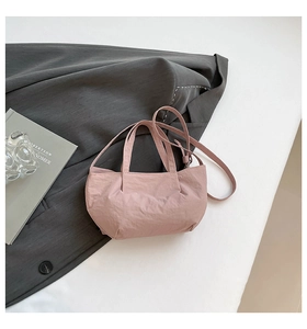 Macro detail of pink pleated fabric handbag showing texture and crossbody strap
