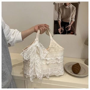 Close-up of cream white lace tote bag with delicate floral trim and large lace bow