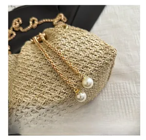 Detail of beige woven bucket bag with gold chain and pearl embellishments