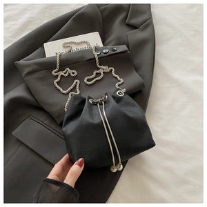 Détail d'un sac seau noir motif crocodile avec cordon à perles et bandoulière chaîne