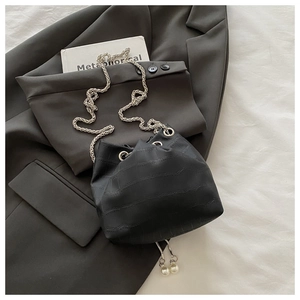Détail du sac seau noir motif crocodile avec chaîne argentée et ornements en perles