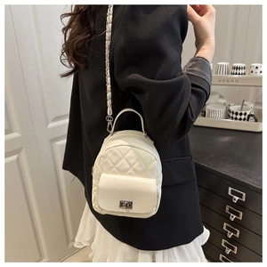 Detailed view of white quilted mini backpack with silver chain strap on model