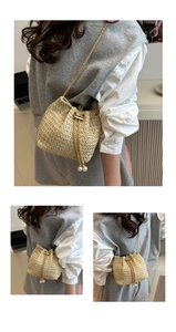 Detailed macro view of woven straw bucket bag with gold chain and pearl drawstrings