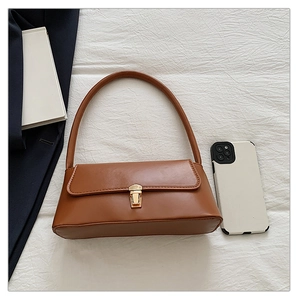 Sac baguette marron en similicuir avec fermoir doré et accessoires lifestyle