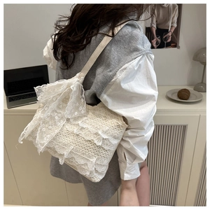 Détail du sac cabas en dentelle blanche orné d'un grand nœud décoratif sur le côté