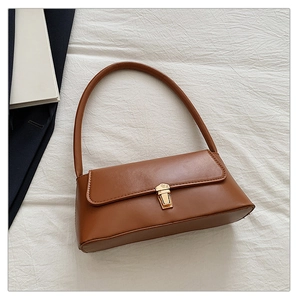 Sac sous le bras marron avec fermoir doré sur fond texturé blanc très élégant
