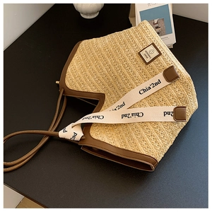 Detail of beige straw tote bag featuring brown leather trim and stylish woven straps