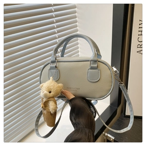 Light blue mini bowling bag with lychee texture and cute bear charm in hand view