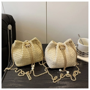 Detail of woven straw bucket bags with pearl charms and golden chain straps in two colors