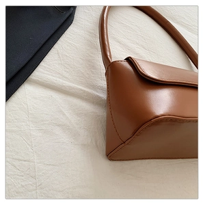 Gros plan d'un sac à bandoulière marron minimaliste en cuir avec coutures fines et poignée