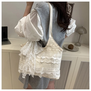 Détail d'un sac cabas en dentelle beige avec volants multicouches et ruban décoratif