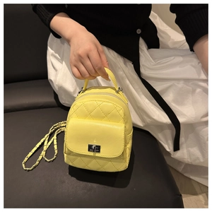Close-up of lemon yellow quilted leather mini backpack held by a model on a sofa